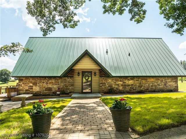 view of front of home with a front yard, stone siding, and metal roof