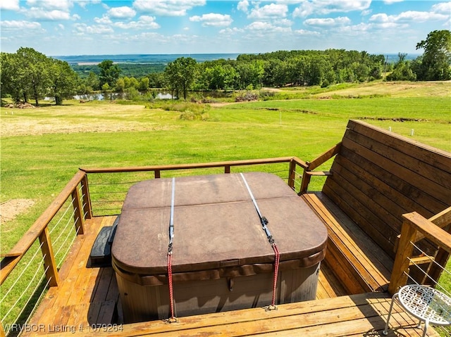 wooden deck with a water view, a hot tub, a lawn, and a rural view