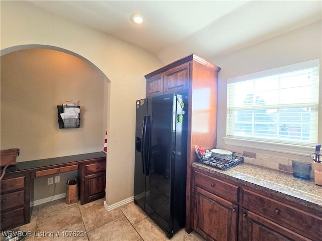 kitchen with light tile patterned floors and black refrigerator with ice dispenser