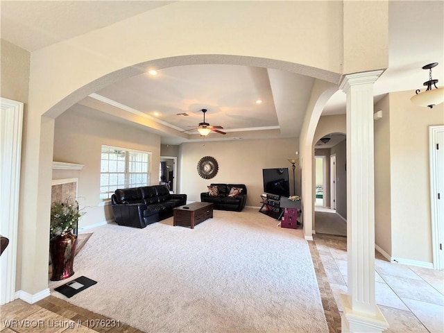 living room featuring ceiling fan, a raised ceiling, light carpet, and decorative columns