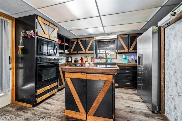 kitchen with black appliances, a paneled ceiling, and light wood-type flooring