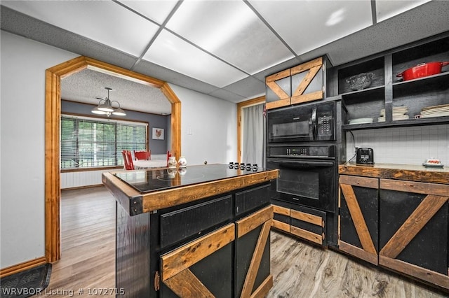 kitchen with light hardwood / wood-style floors, a drop ceiling, and black appliances