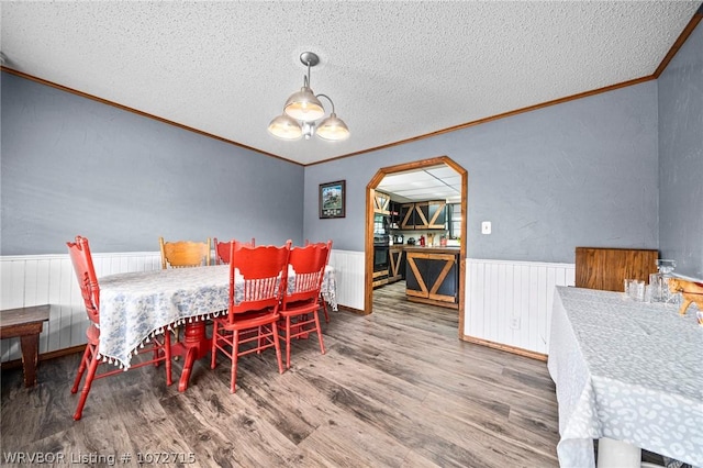 dining area with a chandelier, a textured ceiling, hardwood / wood-style flooring, and crown molding