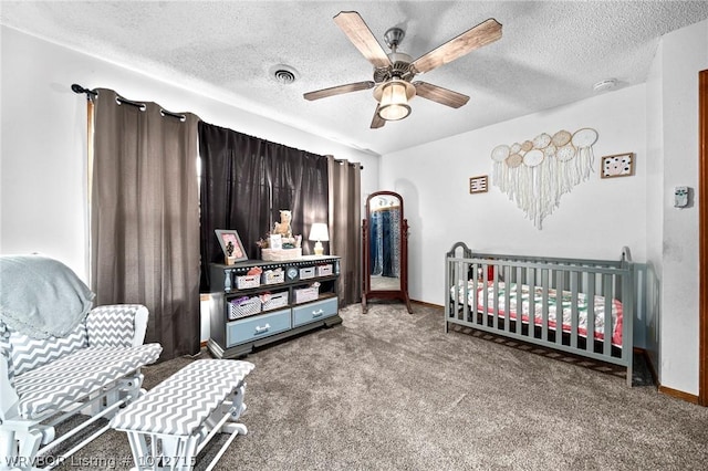 carpeted bedroom with ceiling fan, a textured ceiling, and a nursery area