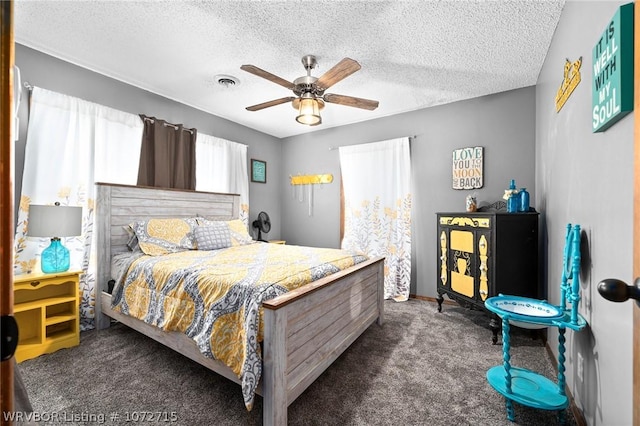 bedroom with dark colored carpet, a textured ceiling, and ceiling fan