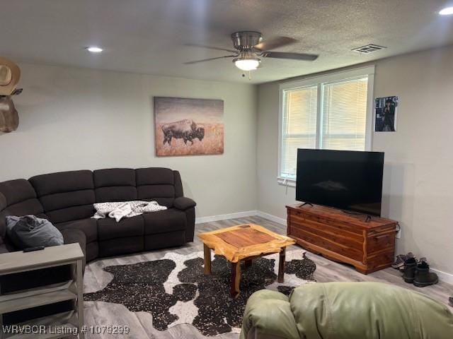 living room featuring visible vents, ceiling fan, baseboards, and wood finished floors