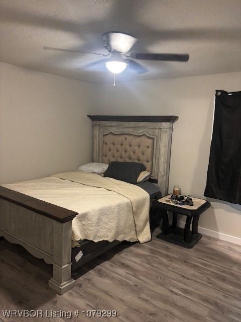 bedroom featuring ceiling fan, wood finished floors, and baseboards