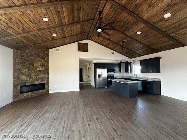 kitchen featuring a center island, open floor plan, a sink, black microwave, and stainless steel fridge