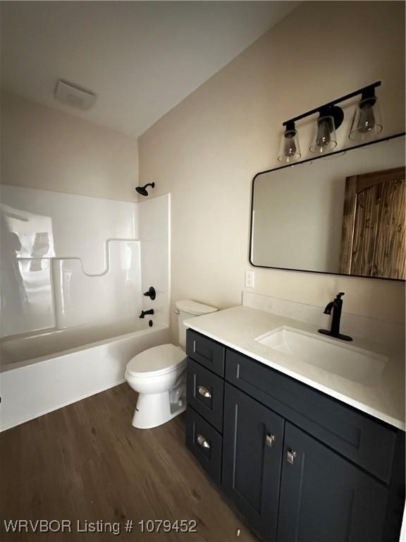 full bathroom with toilet, vanity, wood finished floors, and washtub / shower combination