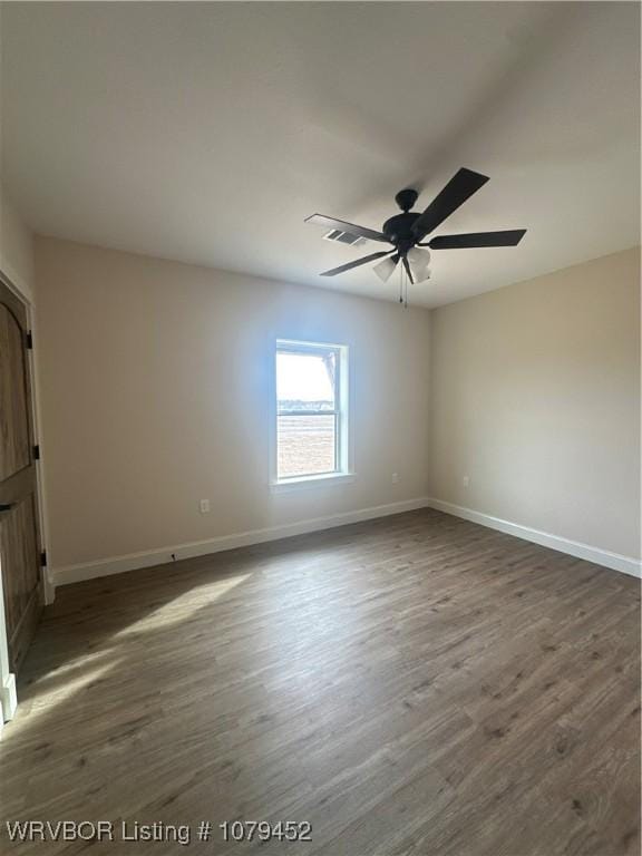 spare room with dark wood-type flooring, visible vents, baseboards, and a ceiling fan