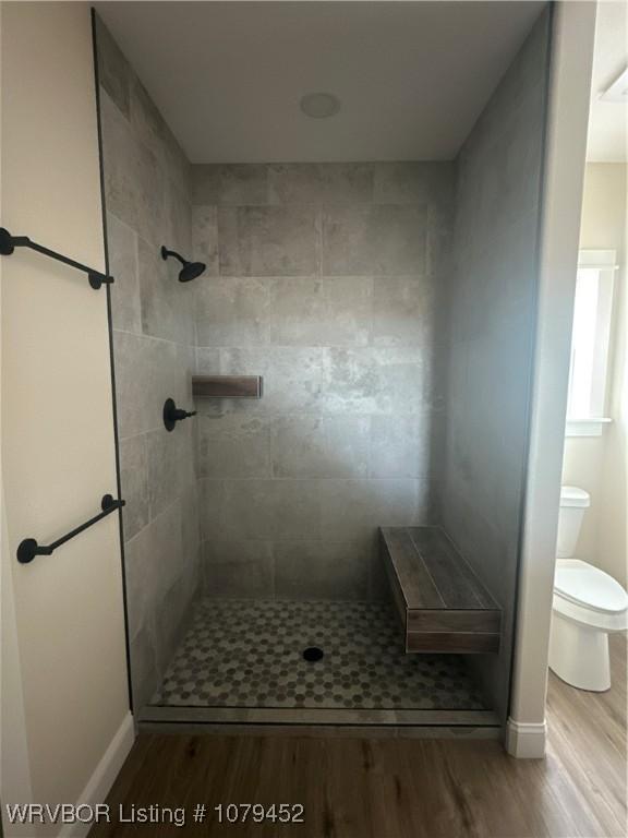 bathroom featuring tiled shower, wood finished floors, and toilet