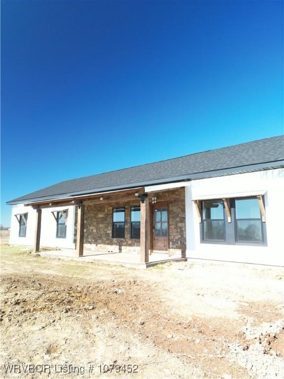 rear view of house featuring roof with shingles