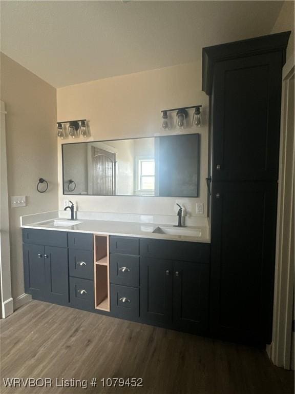 full bath with double vanity, a sink, and wood finished floors