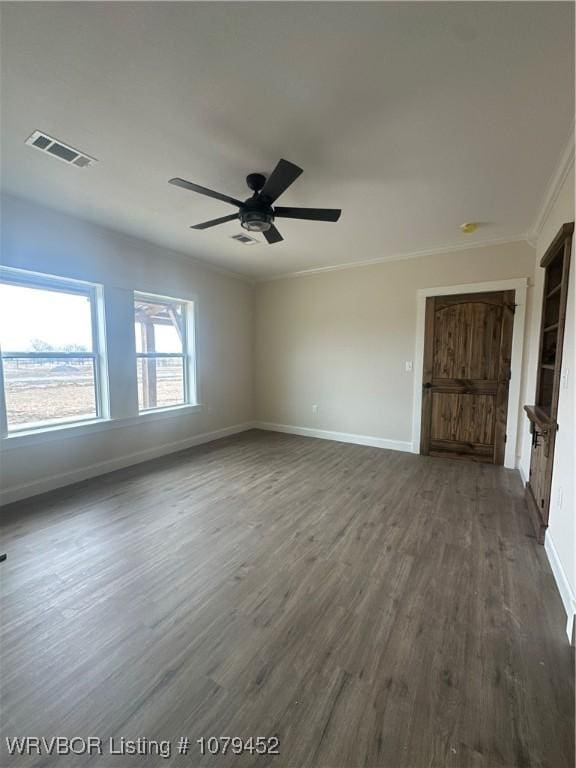 unfurnished room with crown molding, dark wood-style flooring, visible vents, and baseboards