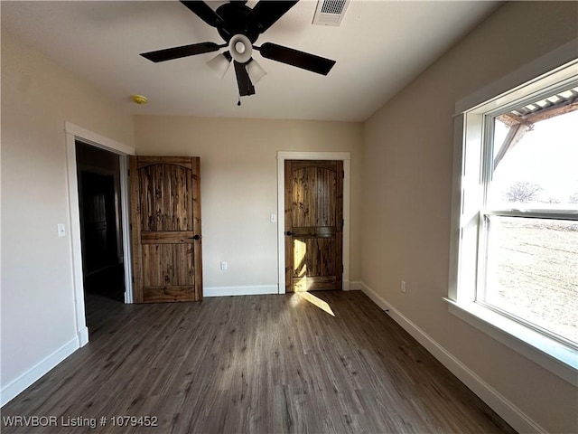 unfurnished bedroom featuring ceiling fan, baseboards, visible vents, and dark wood finished floors