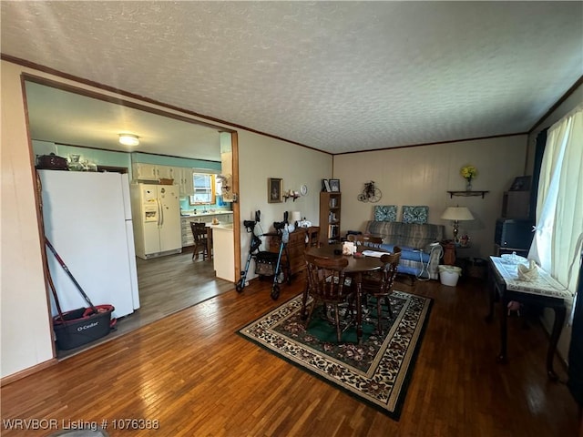 dining area with hardwood / wood-style flooring, crown molding, and a textured ceiling