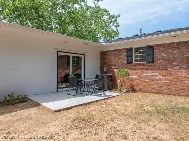 rear view of property featuring central AC unit, brick siding, and a patio