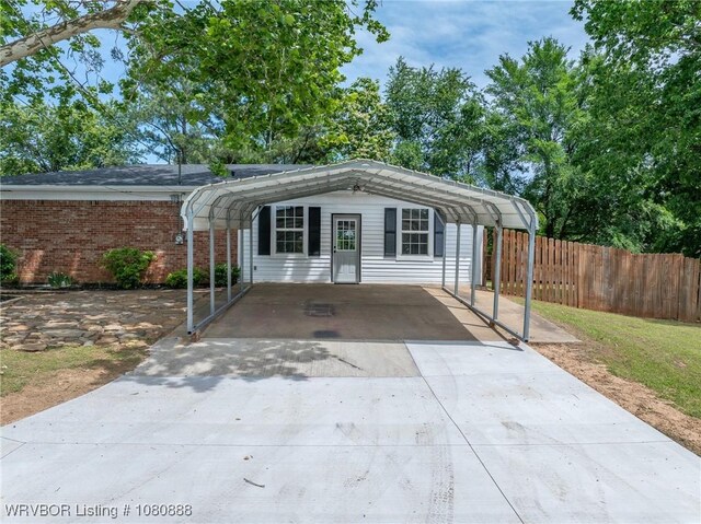 view of front of home featuring fence, concrete driveway, and a detached carport