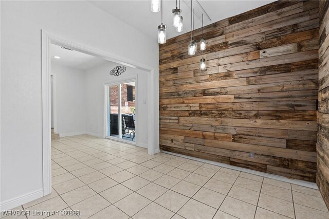 unfurnished room featuring wood walls, light tile patterned floors, and baseboards