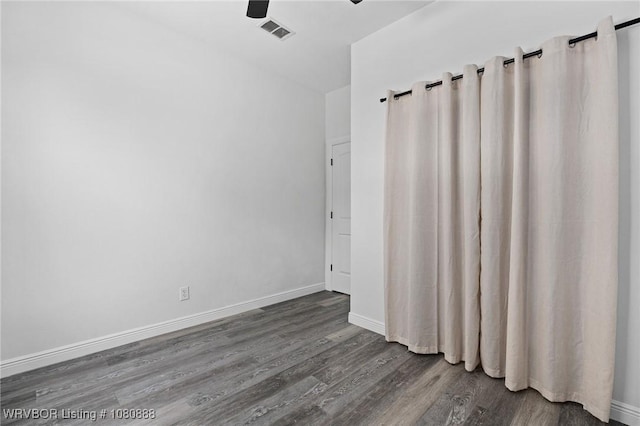 spare room featuring dark wood-type flooring, baseboards, and ceiling fan