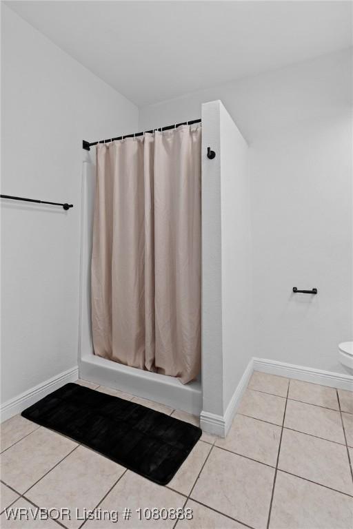 full bathroom featuring tile patterned flooring, a shower with curtain, baseboards, and toilet