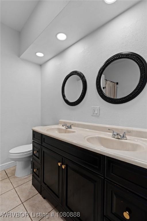 bathroom with tile patterned flooring, double vanity, and toilet