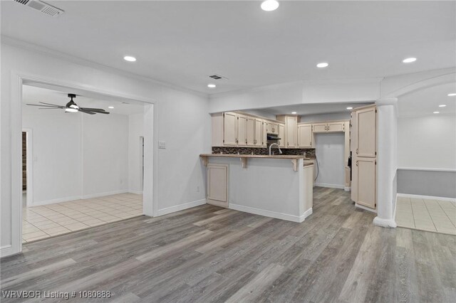 kitchen featuring a peninsula, crown molding, light wood-style flooring, recessed lighting, and a ceiling fan