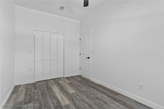 unfurnished bedroom featuring wood finished floors, a closet, baseboards, and ceiling fan