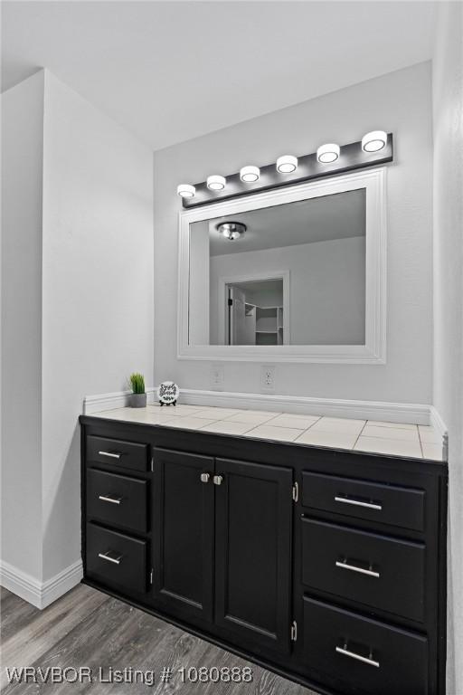 bathroom with wood finished floors, vanity, and baseboards