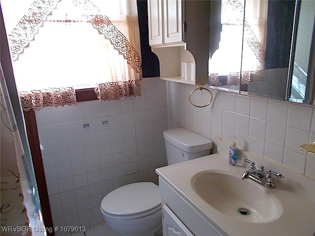 bathroom with vanity, tile walls, and toilet