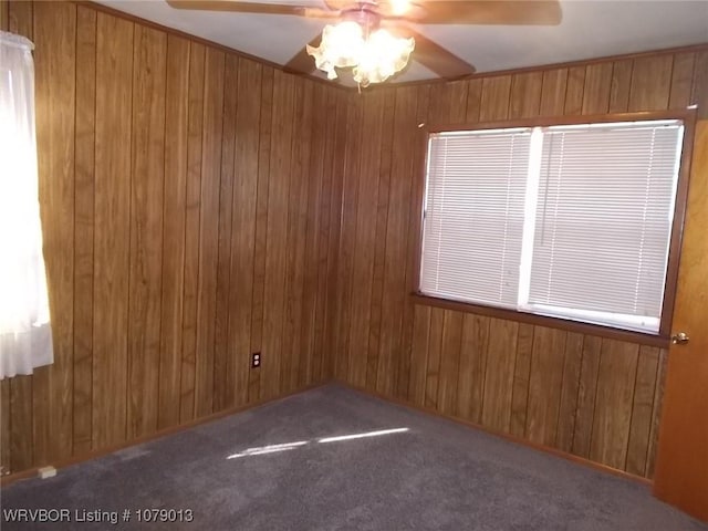 empty room featuring carpet floors, ceiling fan, and wood walls