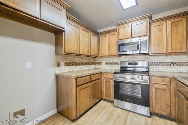 kitchen featuring stainless steel appliances, light wood finished floors, backsplash, and light countertops