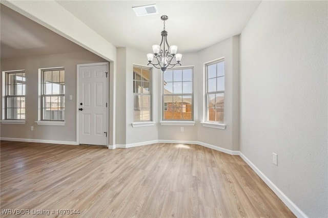 unfurnished dining area with a notable chandelier, visible vents, baseboards, and light wood-style floors