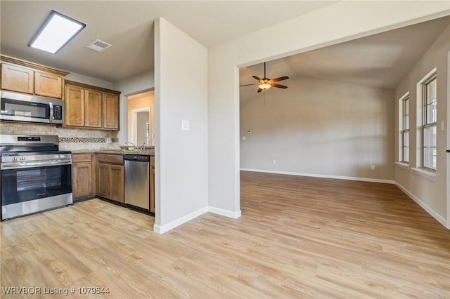 kitchen with brown cabinetry, visible vents, light wood-type flooring, stainless steel appliances, and tasteful backsplash