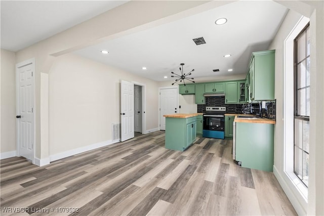 kitchen featuring green cabinetry, stainless steel electric stove, a sink, butcher block countertops, and tasteful backsplash