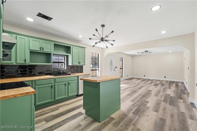 kitchen with visible vents, a sink, green cabinets, butcher block counters, and dishwasher