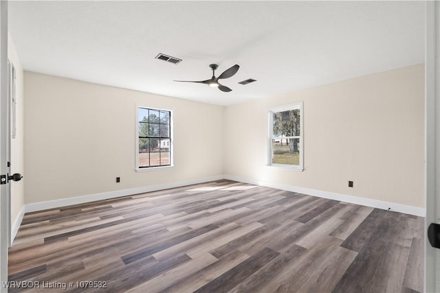 spare room featuring wood finished floors, visible vents, and baseboards