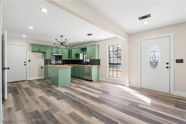 kitchen featuring tasteful backsplash, visible vents, a center island, and green cabinetry