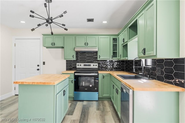 kitchen with under cabinet range hood, butcher block countertops, green cabinetry, stainless steel appliances, and a sink