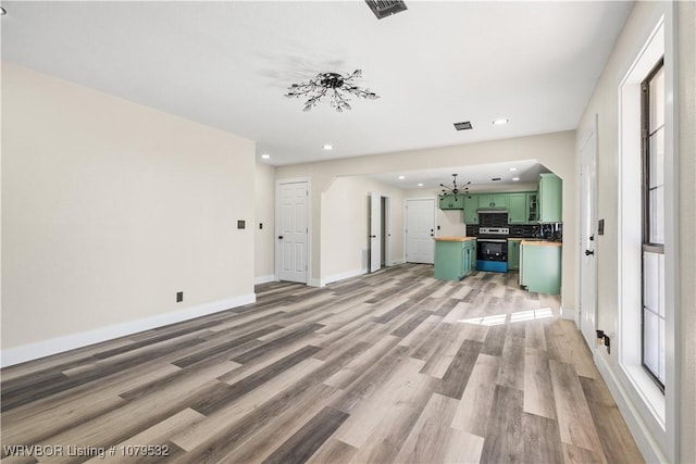 unfurnished living room with light wood-style flooring, recessed lighting, baseboards, and arched walkways