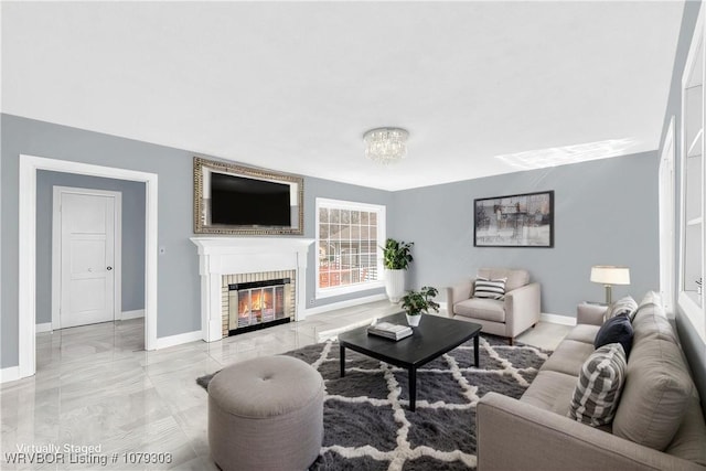 living area with marble finish floor, a fireplace, baseboards, and a chandelier