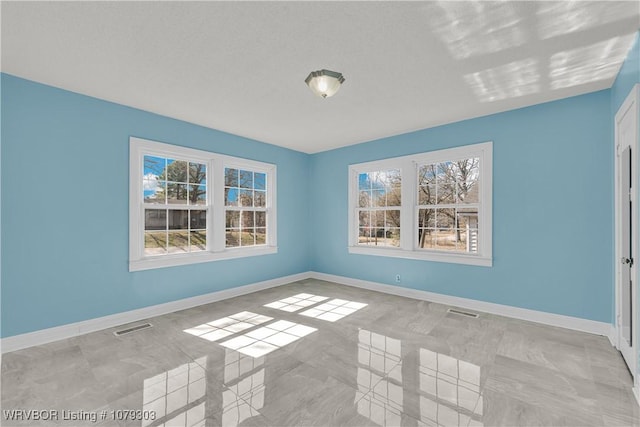 empty room with a healthy amount of sunlight, baseboards, and visible vents