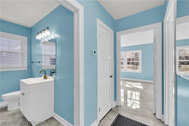 bathroom featuring toilet, marble finish floor, baseboards, and vanity