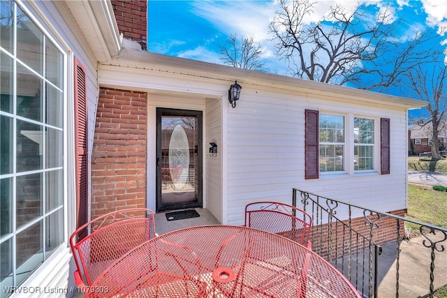 entrance to property with outdoor dining area and brick siding