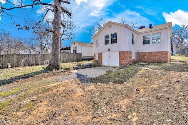 back of house featuring brick siding, a chimney, a patio area, and fence