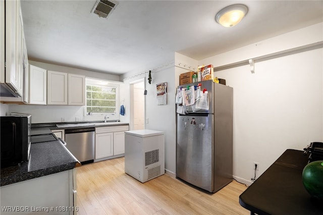 603 Oklahoma Ave, Poteau, OK 74953 - kitchen with stainless steel appliances, light wood-style floors, white cabinetry, and dark countertops