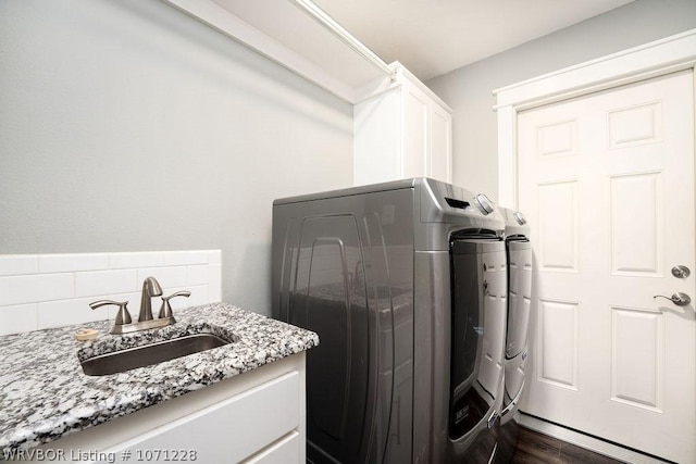 clothes washing area featuring separate washer and dryer, sink, dark hardwood / wood-style flooring, and cabinets