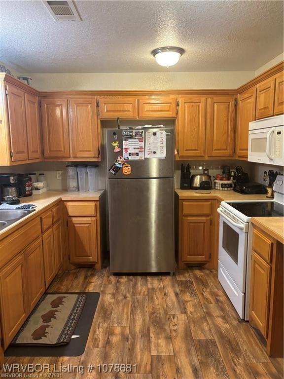 kitchen featuring dark hardwood / wood-style floors, sink, a textured ceiling, and white appliances