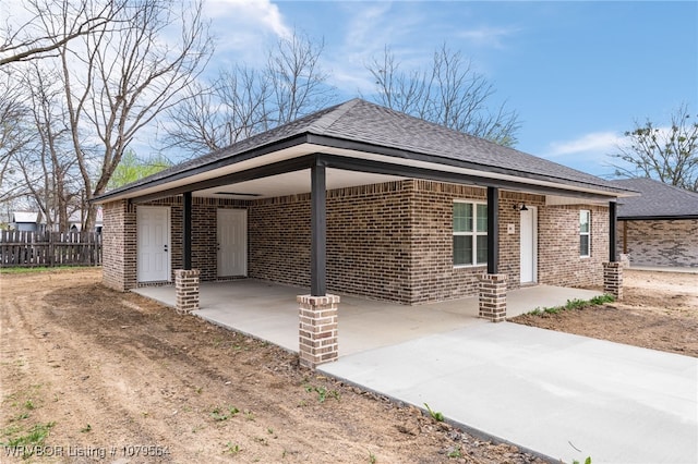 view of front of property featuring brick siding, driveway, a carport, and fence