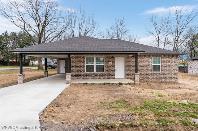 view of front of house with brick siding, concrete driveway, roof with shingles, and a carport